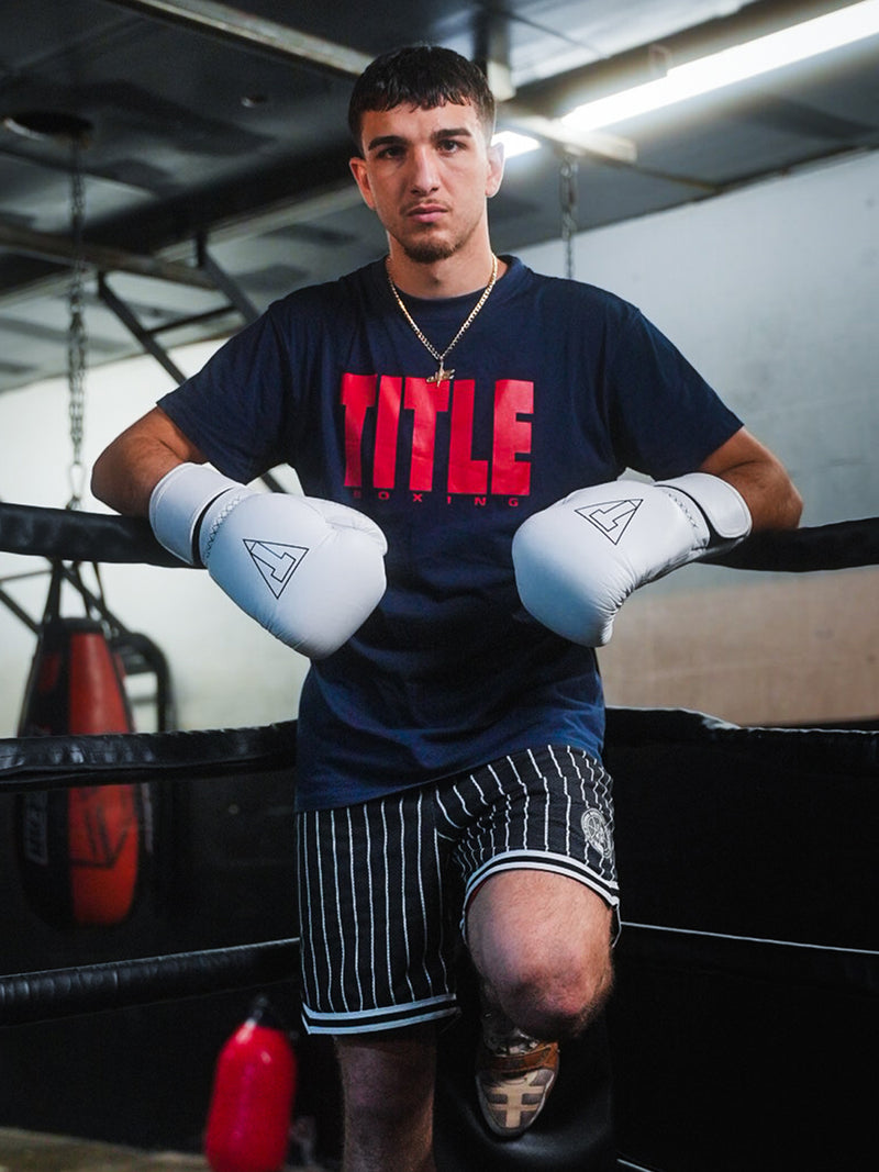 Boxer in a gym wearing a 'Title' shirt and gloves.