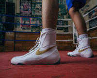 variant:white/gold::Nike Boxing Shoes Machomai 2 close up on shoes guys feet ring