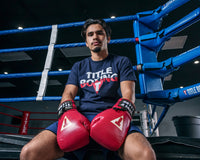 variant:red/white::TITLE Boxeo Mexican Leather Lace Training Gloves Quatro guy sitting on ring