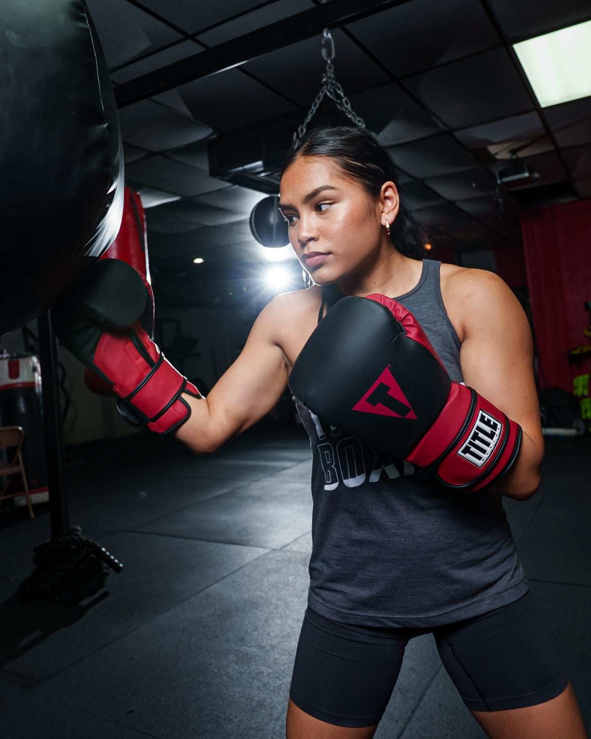 variant:Black/Red::TITLE Boxing Conquest Training Gloves on boxer in the gym hitting bag