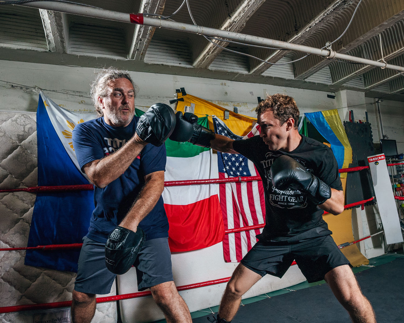 variant:lifestyle::TITLE Black Punch Mitts 2.0 boxer hitting mitts with trainer
