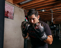 variant:black::TITLE Boxing Peak Bag Boxing Gloves in the gym