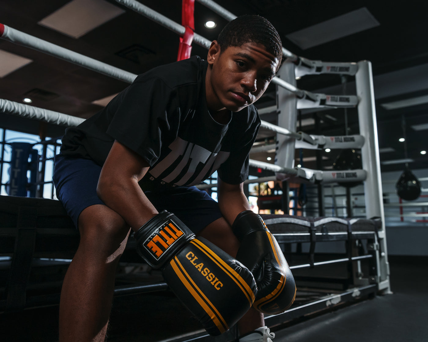 variant:black/gold::TITLE Classic Speed Boxing Gloves kid sitting on edge of ring