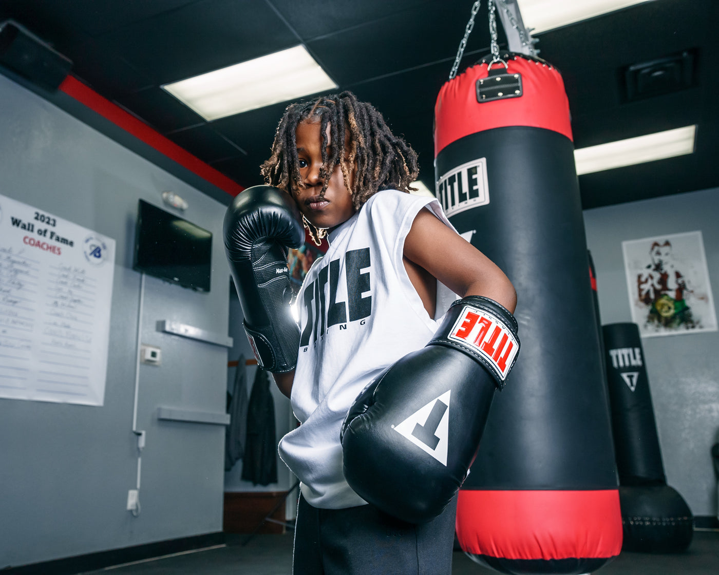variant:lifestyle::TITLE Classic Black Max Boxing Gloves kid boxing stance infront of bag