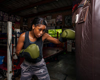 variant:Green/Black::TITLE Boxing Combat Bag Gloves 2.0 Girl punching a bag