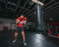 variant:red/white/black::TITLE Classic Leather Super Bag Gloves 2.0 girl hitting heavy bag hands up