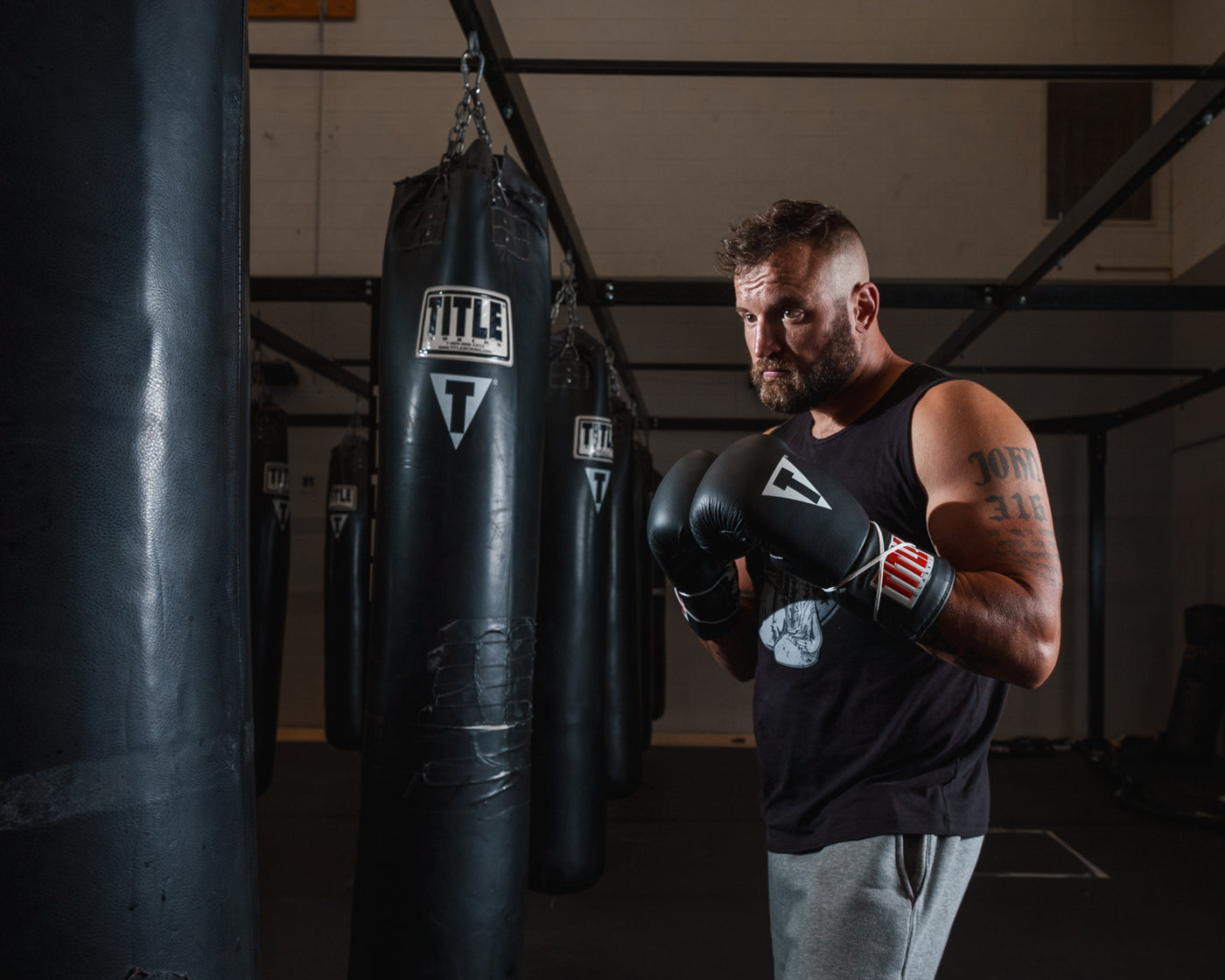 variant:black::TITLE Classic Leather Lace Training Gloves 2.0 guy posing in front of bags