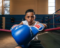 variant:blue/white::TITLE Classic Pro Style Training Gloves 3.0 kid sitting on ring and ropes