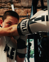 variant:Black/Grey::TITLE Boxing World Bag Boxing Gloves on boxer's hand hitting heavy bag