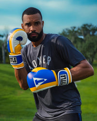 variant:Blue/Yellow/White::TITLE Boxing World Bag Boxing Gloves on boxer's hands in fighting stance