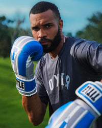 variant:Light Blue/Grey/White::TITLE Boxing World Bag Boxing Gloves on boxer's hands in fighting stance closeup