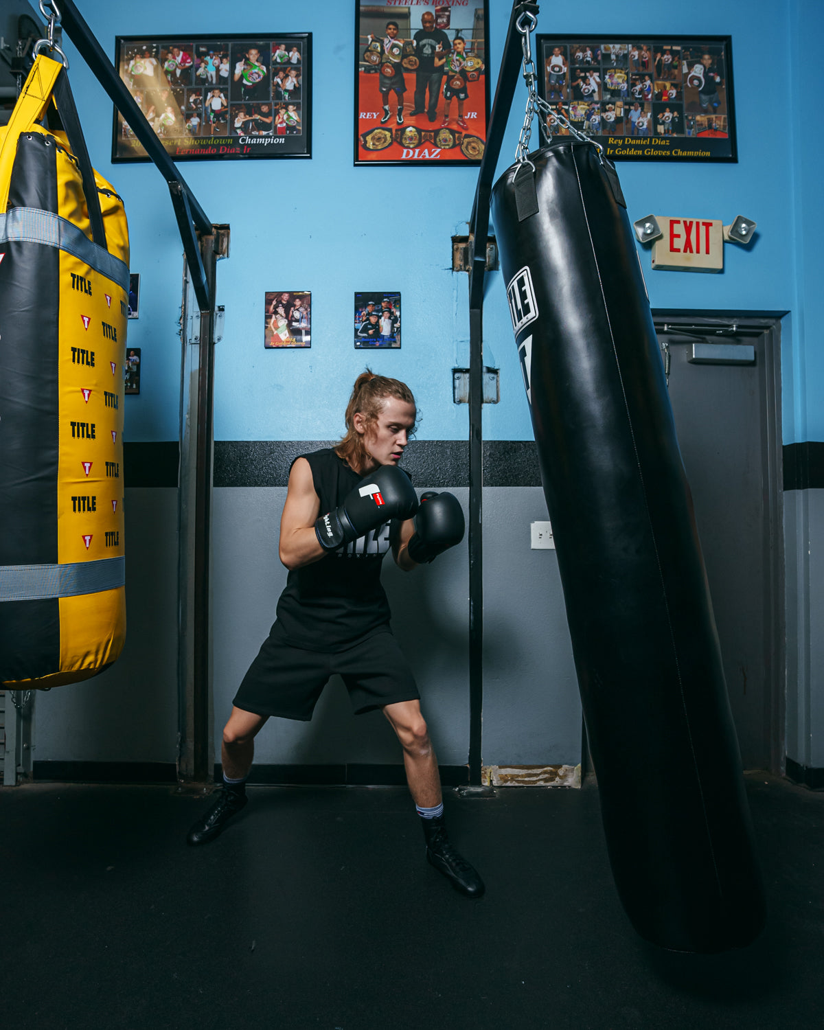 variant:black::Fighting Leather Training Gloves fifth view kid hitting bag