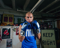 variant:Blue/Black::Fighting Sports Gloves and Wraps Bundle blue/black gloves on fighter in the gym