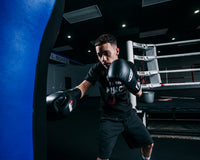 variant:black::Fighting Fury Professional Lace Training Gloves second view guy hitting bag