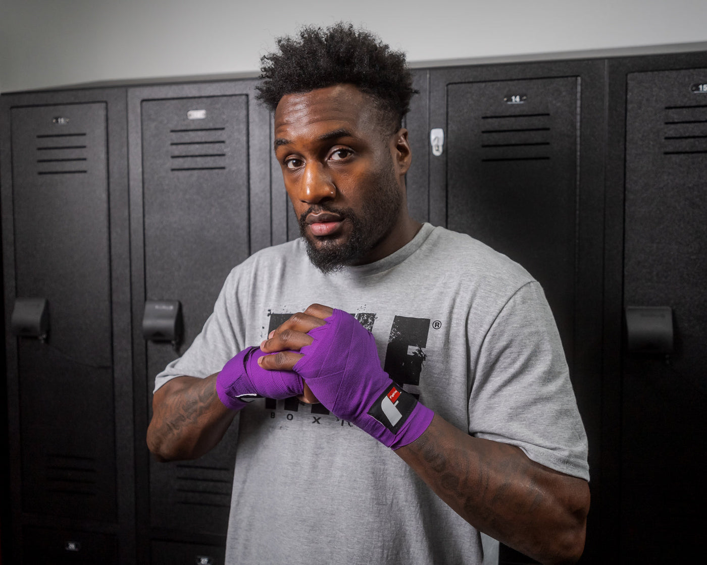 variant:lifestyle::Fighting Sports Gloves and Wraps Bundle fighter showcasing purple wraps in locker room