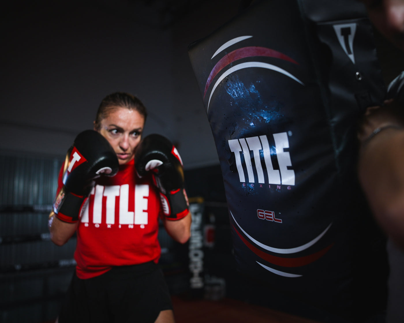 variant:lifestyle::TITLE Boxing Gel Ripple Strike Shield being held by boxing coach with boxer in background