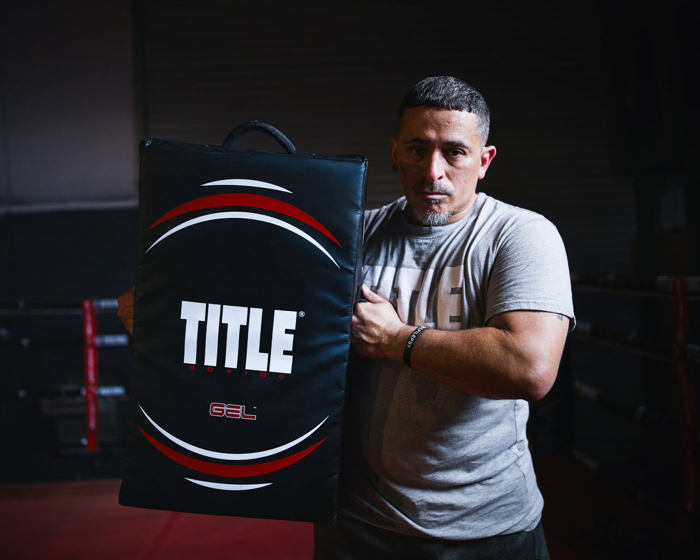 variant:lifestyle::TITLE Boxing Gel Ripple Strike Shield held up by boxing coach