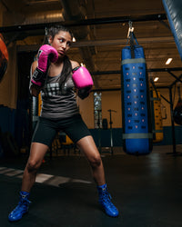 variant:Hot Pink/Black::TITLE Boxing Gel Glory Super Bag Gloves 2.0 girl boxing pose with bag