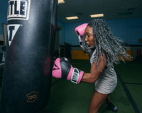 variant:Pink/Black::TITLE Boxing Gel Suspense Training Gloves lady hitting bag left jab close up