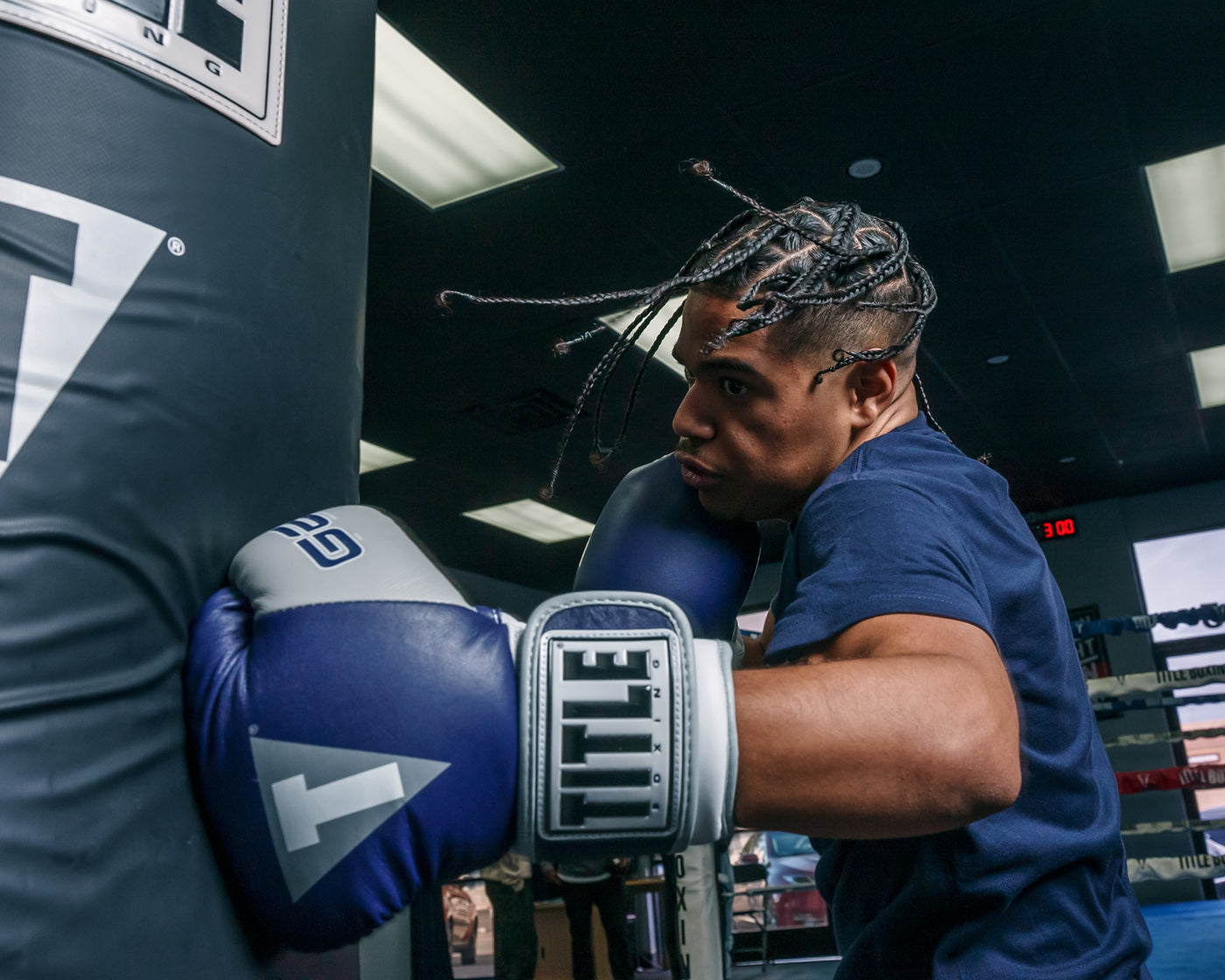 variant:navy::TITLE Boxing Gel World V2T Bag Gloves guy hitting left hook bag