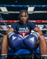 variant:navy::TITLE Boxing Gel World V2T Bag Gloves guy sitting on ring