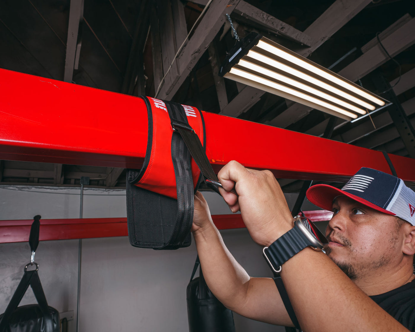 variant:lifestyle::TITLE Boxing Universal Heavy Bag Hanger being set up in a boxing gym