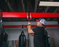 variant:lifestyle::TITLE Boxing Universal Heavy Bag Hanger being installed in a boxing gym