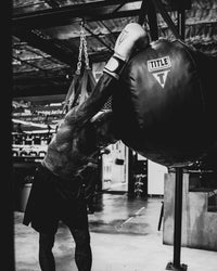variant:lifestyle::TITLE Boxing Body Snatcher Bag in the gym with boxer resting on bag