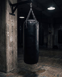 variant:black::TITLE Boxing KO-Vert Heavy Bag hanging in the gym