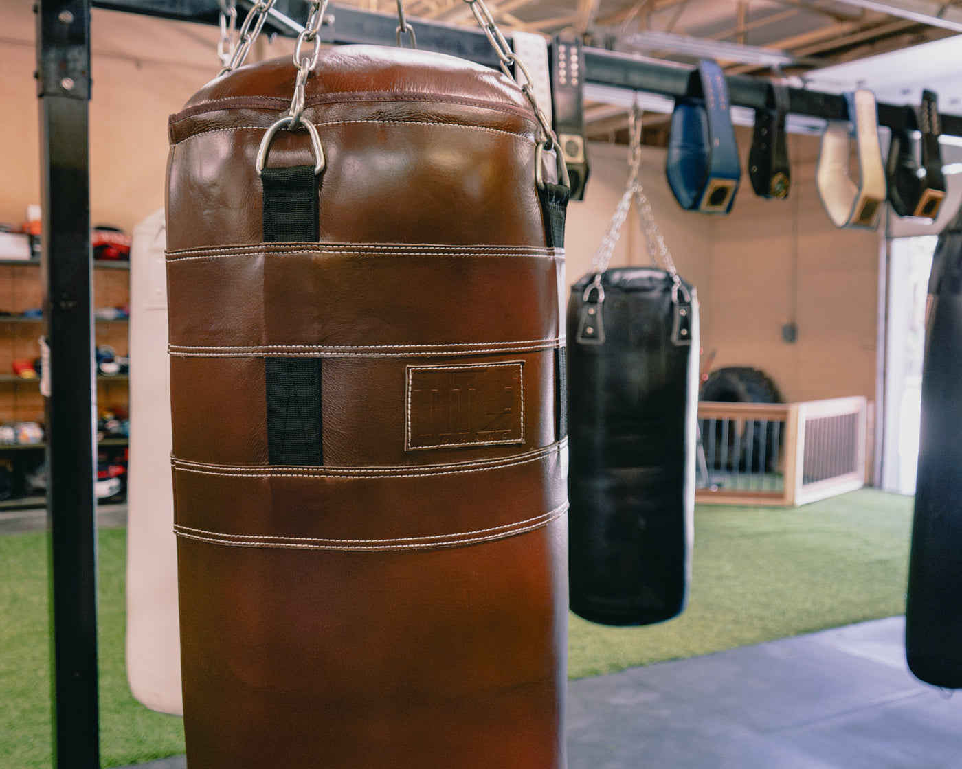 variant:brown::TITLE Boxing KO-Vert Leather Heavy Bag closeup of bag hanging in the gym