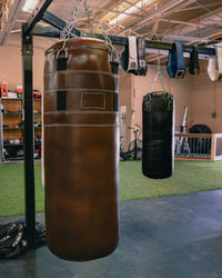 variant:brown::TITLE Boxing KO-Vert Leather Heavy Bag hanging in the gym