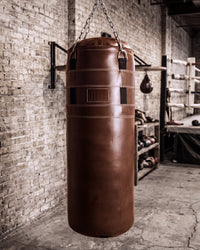 variant:brown::TITLE Boxing KO-Vert Leather Heavy Bag hanging in the gym