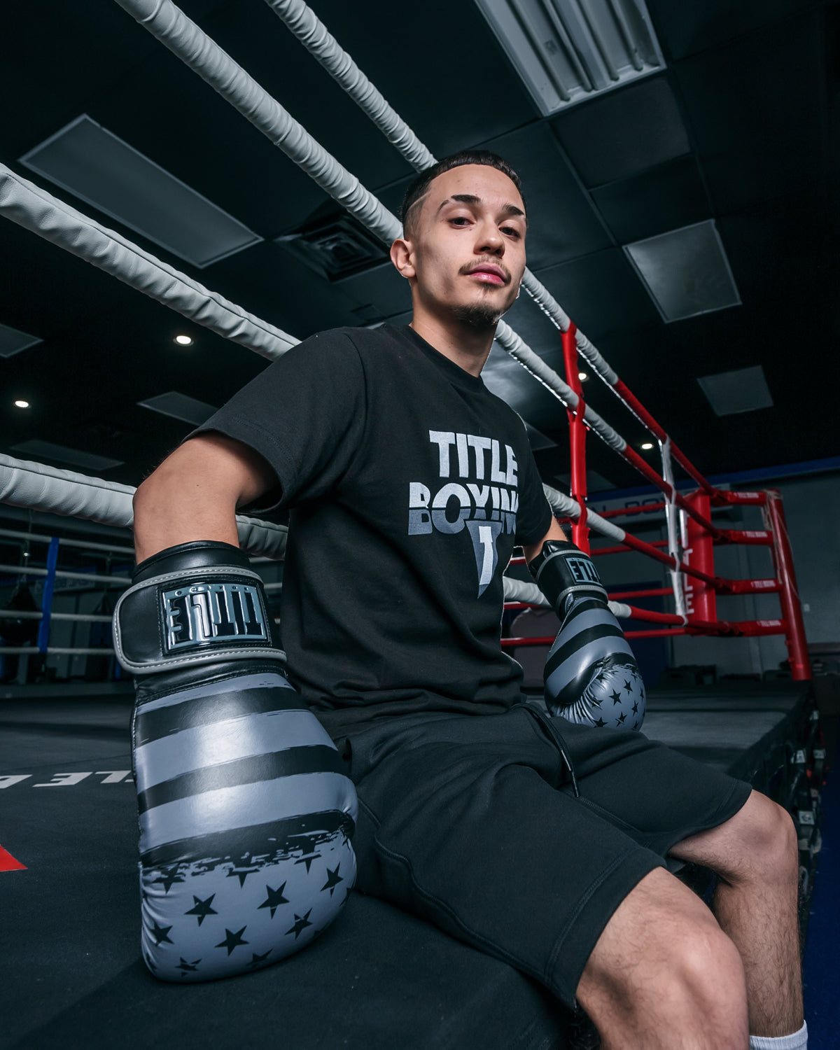 variant:black/grey::TITLE Boxing Liberty Bag Gloves guy sitting on ring