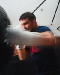 variant:white::TITLE Boxing Momentum Pro Bag Gloves on boxer's hands punching bag