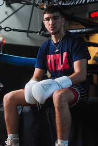 variant:white::TITLE Boxing Momentum Pro Bag Gloves on boxer's hands in front of ring
