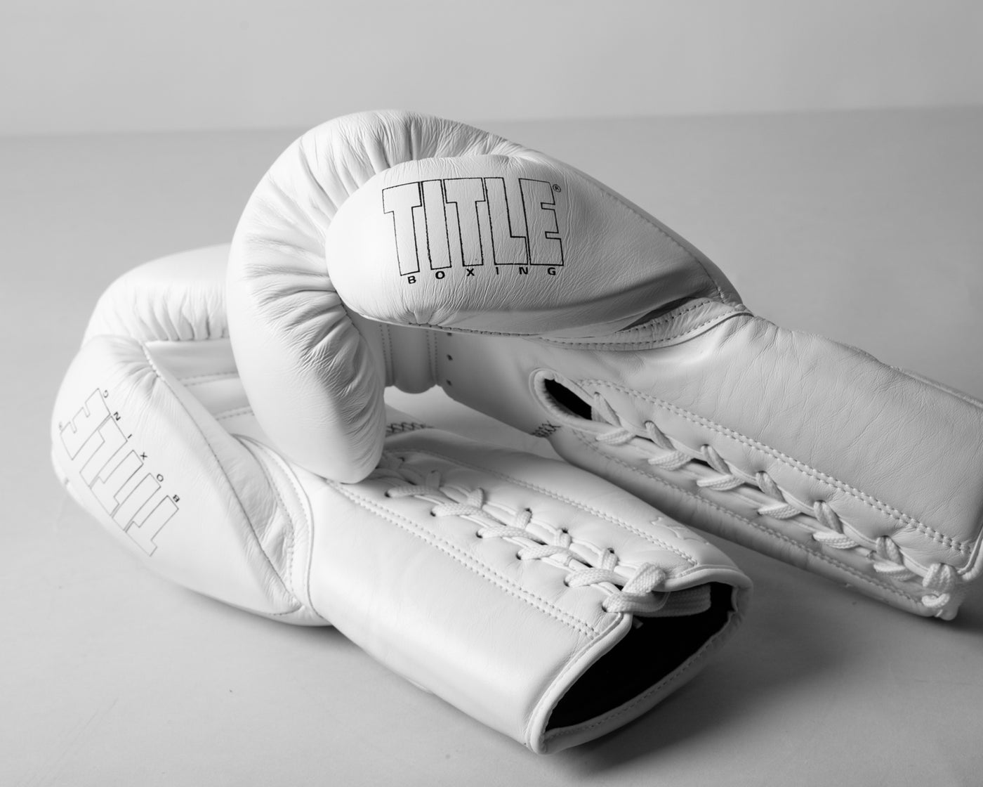 variant:white::TITLE Boxing Momentum Pro Sparring Gloves laying flat with thumb logo visible