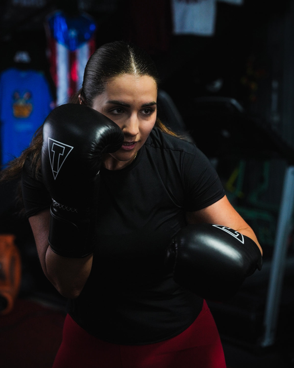 variant:black::TITLE Boxing Momentum Pro Training Gloves on boxer hitting bag