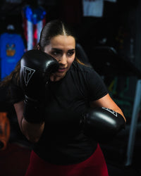 variant:black::TITLE Boxing Momentum Pro Training Gloves on boxer hitting bag