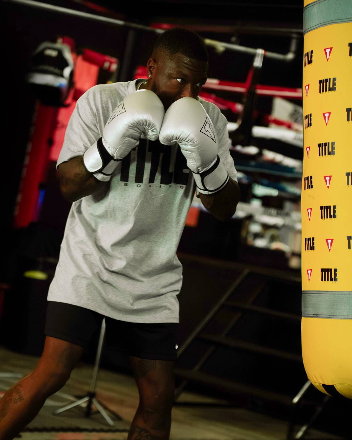 variant:Silver/Black::TITLE Boxing Momentum Pro Training Gloves boxer hitting heavy bag in the gym with gloves on