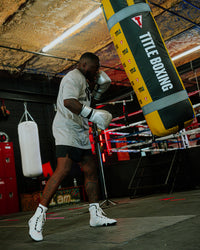 variant:Silver/Black::TITLE Boxing Momentum Pro Training Gloves boxer hitting heavy bag in the gym with gloves on