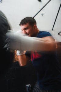 variant:white::TITLE Boxing Momentum Pro Training Gloves on boxer's hand punching bag