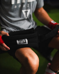 variant:lifestyle::TITLE Boxing Neck Strengthener 2.0 in boxer's hands in the gym