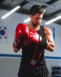 variant:red/black::TITLE Boxing Oversize SAFE-T Contact Gloves on boxer in the gym taking off gloves