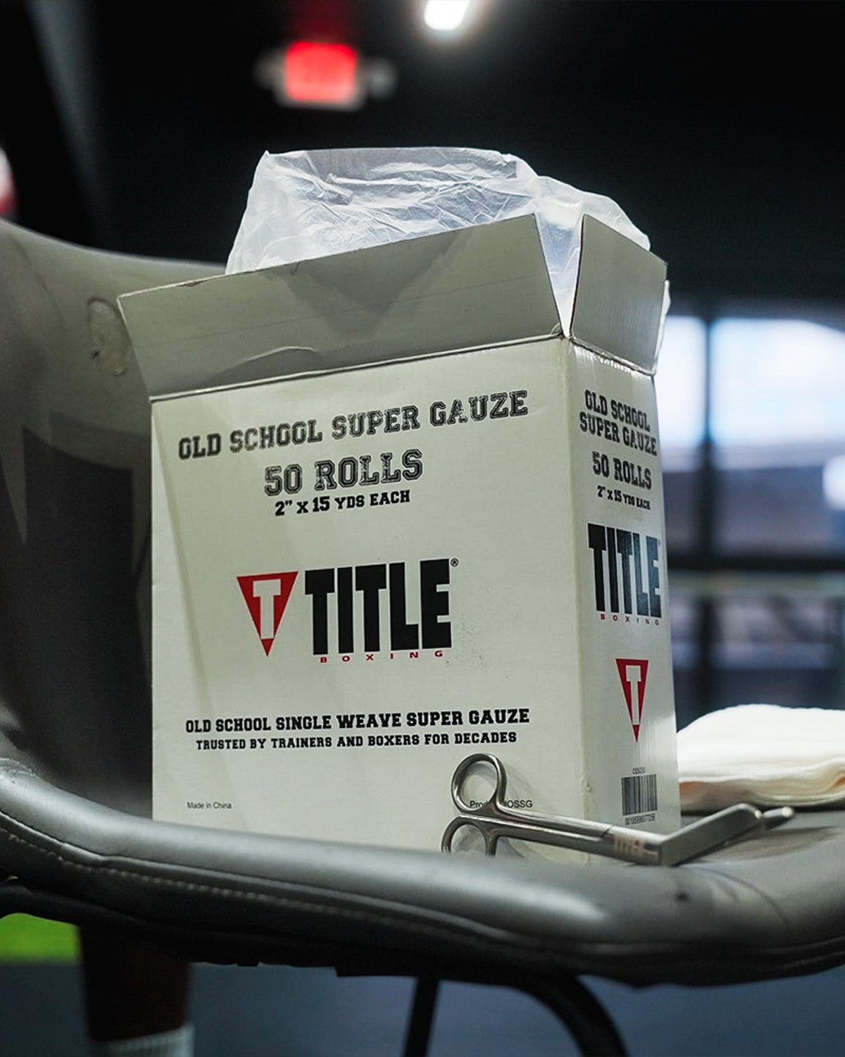 variant:lifestyle::TITLE Boxing Old School Super Gauze (50 Rolls) box of gauze in a chair with scissors