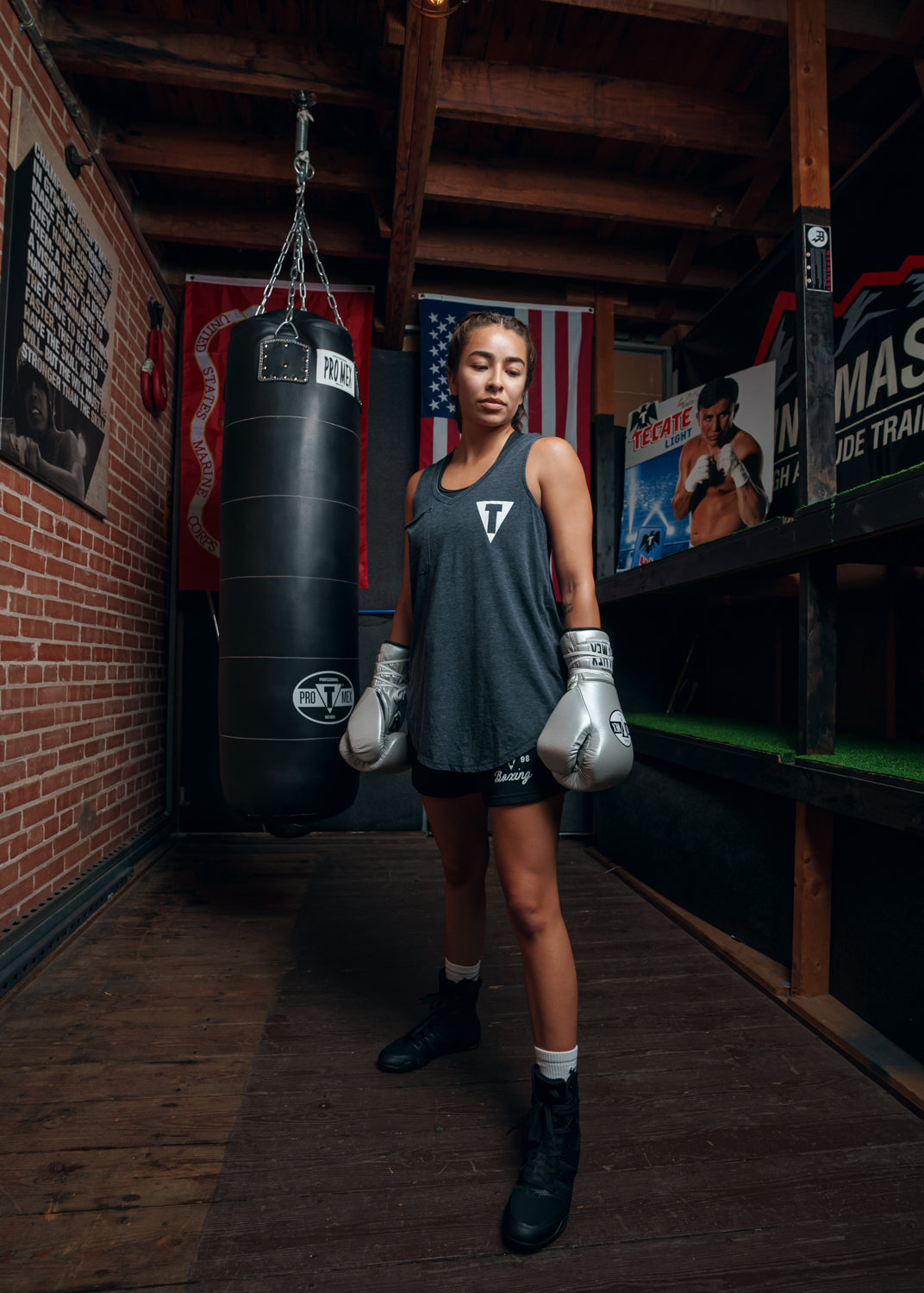 variant:silver::Pro Mex Professional Lace Sparring Gloves V3.0 girl standing infront of bag