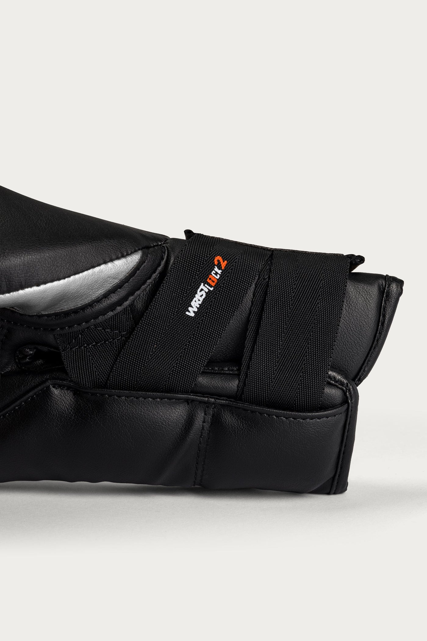 variant:Silver::Close-up of a black martial arts grappling sleeve with a hook-and-loop strap closure, featuring the West 1st 2 logo in white and orange, set against a light gray background.