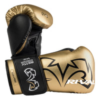 color:Gold::A pair of Rival boxing gloves in metallic gold and black, displayed against a solid white background. The gloves feature the Rival brand logo in black on the gold leather, a black wrist strap with white branding, and a gold knuckle pad.