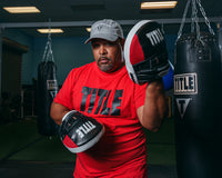 variant:lifestyle::TITLE Boxing Aerovent Excel Incredi-Mitts 2.0 boxer red shirt holding up mitts