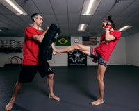variant:lifestyle::TITLE Boxing Pro Punch Shield 2.0 coach with lady kicking shield