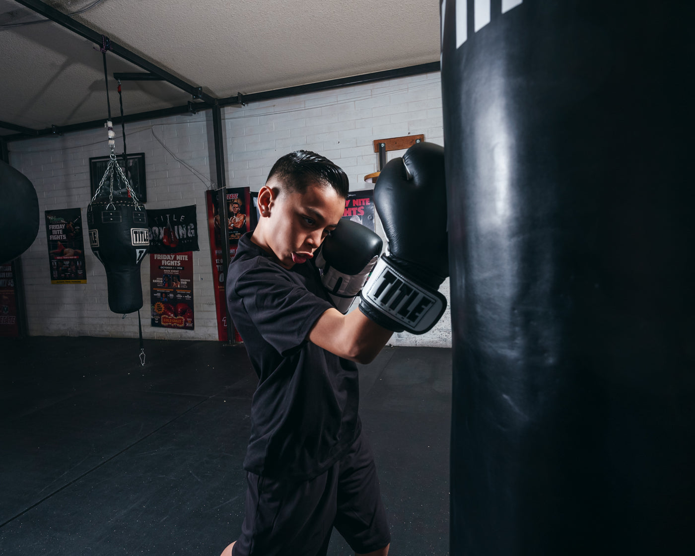 variant:Black/White::TITLE Premier Leather Super Bag Gloves 2.0 in use with a heavy bag
